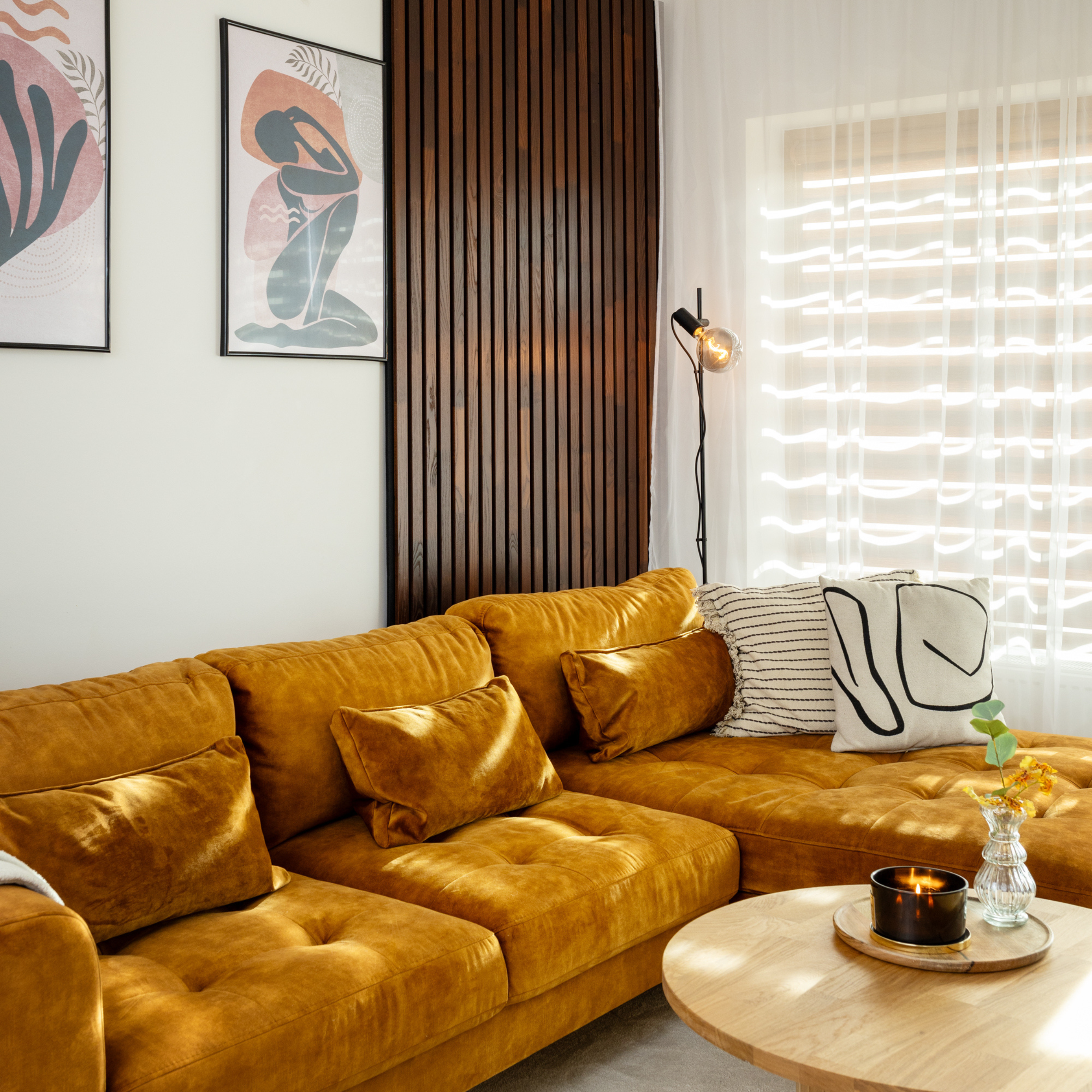 Natural termoash solid wood acoustic panels on a modern and cosy living room wall with a yellow couch and solid wood coffee table