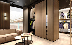 A modern and cozy closet space with dark solid wood acoustic panels and round coffee tables with a light couch in the background